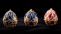 Luxurious decorative eggs with ornate golden filigree pattern on blue and pink enamel background arranged in row on dark surface, jewelry art piece design.