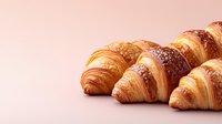 Fresh baked butter croissants with flaky golden layers and crispy crust on pink background, morning breakfast pastry concept for cafe menu or bakery.