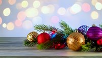 Festive Christmas ornaments and pine branches on wooden surface with soft bokeh background creating holiday atmosphere.