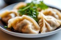 Steamed Asian dumplings with tender dough wrapper filled with savory meat and vegetables, garnished with fresh herbs on ceramic plate, macro food photography.