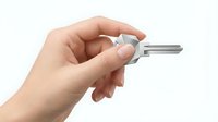 Hand holding silver metal key isolated on white background for security access and property concepts.