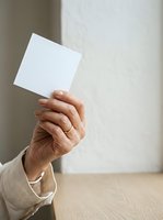 Mature adult male hand holding blank white card against neutral background, suitable for business messaging and corporate communications.