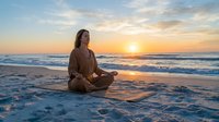 Young Caucasian woman meditating in lotus pose on beach at golden sunset, practicing mindfulness yoga by the ocean waves.