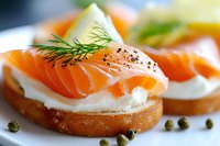 Fresh smoked salmon canapes with cream cheese, dill garnish and capers on toasted bread rounds, served on white plate. Close up view with selective focus.