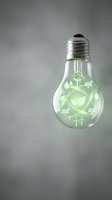 Light bulb with green eco-friendly symbols including solar panels, wind turbines, leaves and water drops representing sustainable energy innovation.