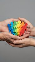 Hands holding colorful paper cutout people figures representing diversity, inclusion, teamwork and community support in workplace or social groups.