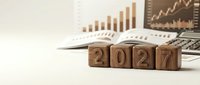 Wooden blocks displaying 2027 with financial charts, graphs and calculator on desk representing business planning and year-end analysis.