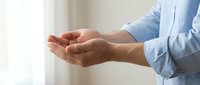 Professional cupped hands gesture in light blue shirt showing care, support and offering help in bright indoor setting for business presentations.