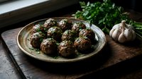 Homemade meatballs with fresh herbs on rustic ceramic plate. Traditional comfort food recipe with parsley garnish and garlic on wooden cutting board.
