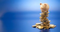 Pink piggy bank sitting on stack of golden coins against blue gradient background for savings and investment concepts.