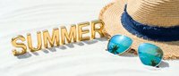 Gold letters spelling SUMMER on white sand beside a straw hat and aviator sunglasses reflecting palm trees, evoking a tropical beach vacation mood.