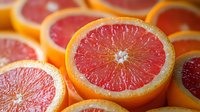 Fresh ripe pink grapefruit halves showing juicy pulp texture and vibrant citrus segments in macro close up view, natural organic healthy food background pattern.