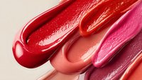 Glossy lipstick swatches in various shades of red and pink, showcasing vibrant cosmetic colors for beauty product marketing.