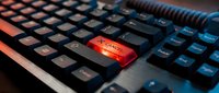 Close-up of black computer keyboard with glowing red Enter key, modern gaming setup with RGB lighting effects for technology and digital workspace concepts.