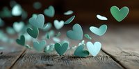 Delicate teal paper hearts scattered on rustic wooden surface, creating romantic atmosphere for Valentine's Day, wedding, or anniversary celebrations.