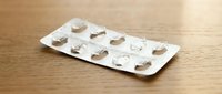Empty medication blister pack on wooden surface showing used pill compartments for healthcare and pharmaceutical concepts.