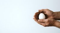 Male hand with medium-dark skin tone holding white sphere isolated on light background, suitable for business, technology, and design concepts.