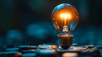 Glowing light bulb with warm filament on scattered coins representing innovation, financial success, and bright investment ideas for business growth.