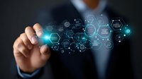 Asian businessman in dark suit pointing at glowing blue hexagonal network interface with digital icons and connections floating in space. Technology concept.