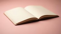 Open blank notebook with empty pages on soft pink background for writing, journaling, planning and creative projects.