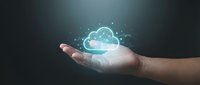 Hand holding glowing cloud computing icon with network connections and digital particles on dark background for technology concepts.