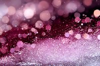 Pink and burgundy glowing bokeh lights with sparkling glitter particles on dark background create magical festive atmosphere for holiday designs.