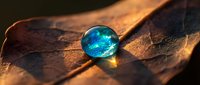 Glowing blue crystal sphere resting on textured brown leather surface with warm golden lighting creating mystical atmospheric mood for fantasy designs.