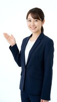 Professional Asian businesswoman in navy suit presenting with open palm gesture on white background for corporate marketing materials.