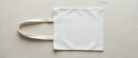 Blank white canvas tote bag with natural handles, isolated on neutral background, ready for custom design, branding, printing, or merchandise mockup projects.