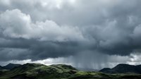 Dramatic storm clouds gather over rolling green mountains under moody sky, conveying weather patterns and atmospheric conditions for environmental and nature projects.