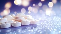 White round medical pills scattered on reflective surface with soft bokeh lights and sparkles in blue and purple tones creating dreamy pharmaceutical background.
