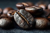 Macro shot of dark roasted coffee beans with visible groove on black background, highlighting rich texture and deep brown color for food marketing.