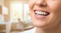 Young woman with metal braces smiling showing orthodontic treatment in dental office for teeth straightening and oral health care.