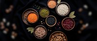 Assorted legumes and pulses in wooden bowls on dark background. Variety of beans, lentils, chickpeas and nuts arranged for healthy cooking and nutrition.