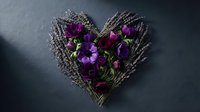 Purple pansies arranged in rustic wicker heart shape on dark slate background for romantic floral decoration and Valentine's Day greeting cards.