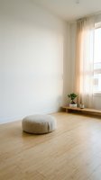 Minimalist living room interior with beige floor cushion, wooden flooring, white walls, natural light from window with sheer curtains and small plant.