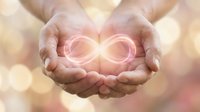 Cupped hands holding glowing infinity symbol with warm bokeh light background representing eternal love, endless possibilities and spiritual connection.