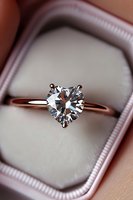 Heart-shaped diamond solitaire engagement ring in rose gold setting nestled in luxurious velvet ring box, showcasing brilliant cut and sparkling facets.