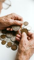 Senior adult hands examining vintage coins on white surface, representing numismatic collecting, retirement savings, and antique currency valuation for educational and financial content.