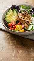 Grilled chicken breast sliced over mixed greens, avocado, tomato, cucumber, and red onion in a bowl. Healthy lunch or dinner meal for nutrition, wellness, and food blogging.