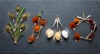 Colorful spices and herbs arranged to spell LOVE on dark slate background. Culinary art concept for cooking, seasoning, kitchen decor and food styling projects.