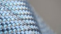 Metallic woven mesh texture with silver and blue tones creating geometric pattern for industrial design backgrounds and modern architectural elements.