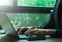 Businessman working on laptop with green energy holographic icons displaying renewable power solutions for sustainable business technology.