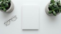 Minimalist white notebook mockup with eyeglasses and green plants on clean desk surface for branding, stationery design and business presentation.