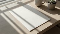 Blank white paper sheet on wooden desk with natural sunlight shadows from window blinds creating striped pattern. Minimalist workspace setup for writing or design.