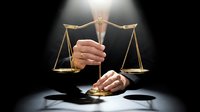 Judge holding golden scales of justice with gavel on desk in dramatic lighting for legal concepts and courtroom decisions.