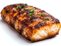 Grilled salmon fillet with crispy caramelized crust and fresh herbs garnish on white background, close-up view showing moist, flaky texture and char marks.