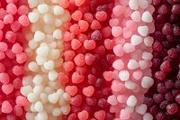 Rows of heart-shaped gummy candies in gradient shades from white to deep red creating romantic pattern background for Valentine's Day designs and sweet treats.
