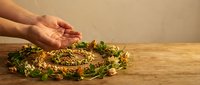 Hands protecting golden crown of thorns with green leaves on wooden surface, symbolizing care, protection, faith and spiritual devotion in religious context.