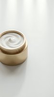 Luxury skincare cream in gold jar with swirled white texture on neutral background, ideal for cosmetics and beauty product marketing.